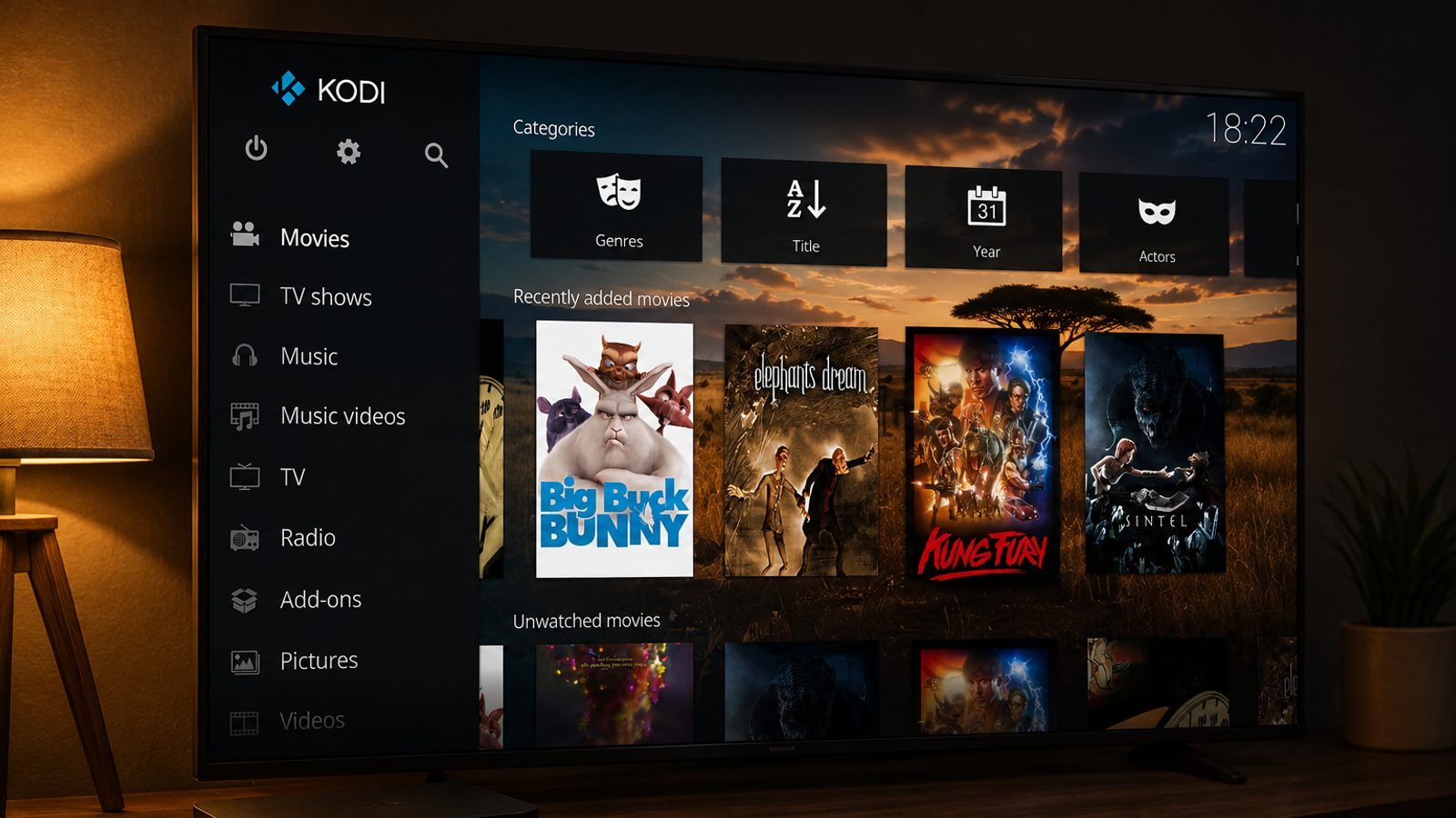 TV box i daljinski pored televizora s medijskim centrom na ekranu u zamračenoj sobi